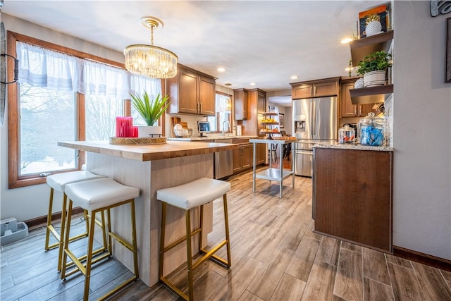 kitchen featuring a kitchen breakfast bar, stainless steel fridge, hanging light fixtures, and a notable chandelier