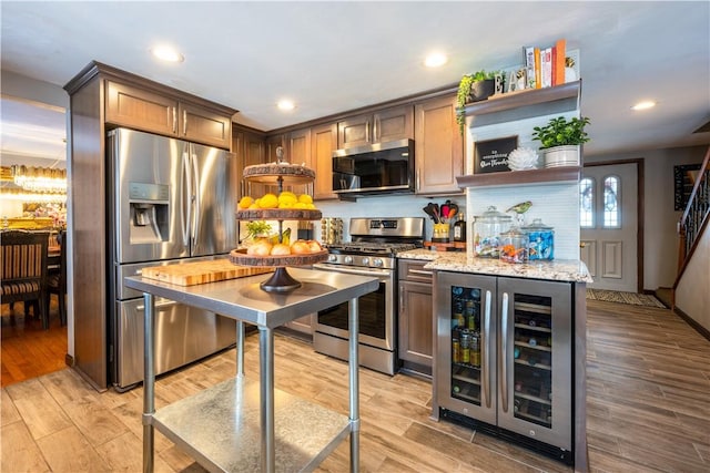 kitchen with wine cooler, appliances with stainless steel finishes, and light stone counters