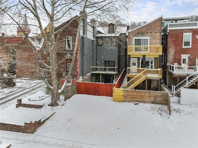 snow covered rear of property featuring a balcony