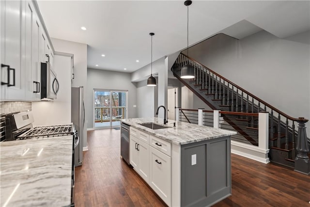 kitchen featuring decorative light fixtures, sink, appliances with stainless steel finishes, white cabinets, and light stone counters