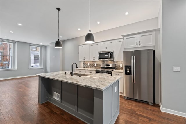 kitchen with pendant lighting, sink, white cabinetry, light stone countertops, and stainless steel appliances