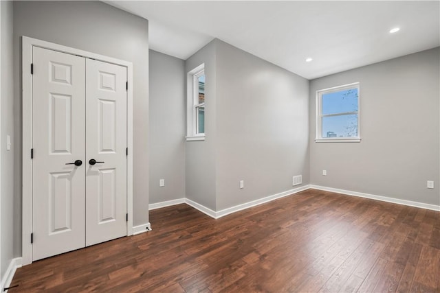 interior space featuring a closet, dark hardwood / wood-style flooring, and multiple windows