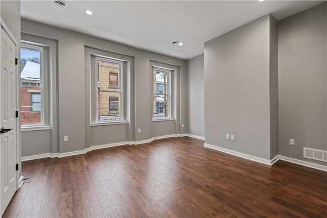 empty room with a wealth of natural light and dark hardwood / wood-style floors