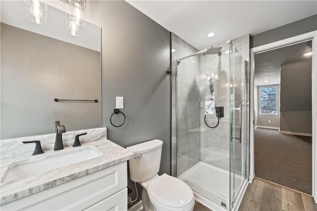 bathroom with toilet, wood-type flooring, a shower with door, and vanity