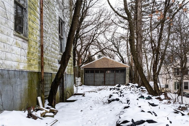 view of snowy exterior with a garage and an outbuilding