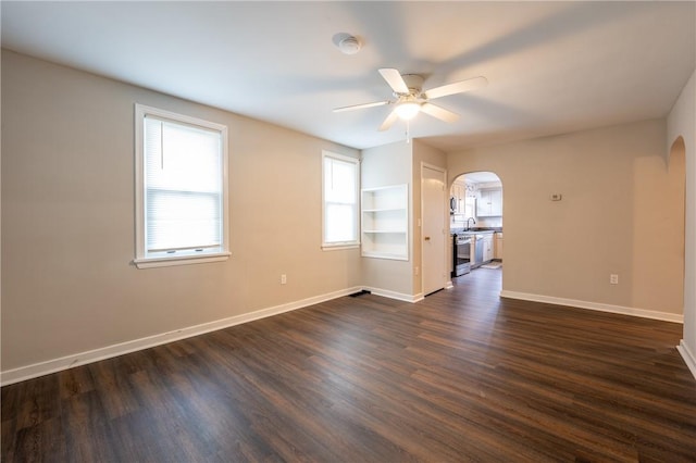 unfurnished room with ceiling fan, dark wood-type flooring, built in shelves, and sink