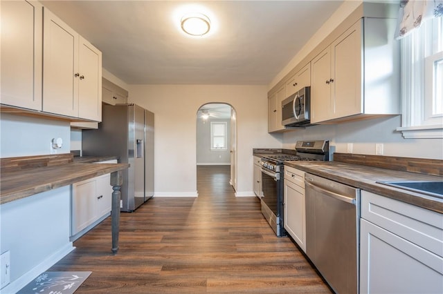 kitchen featuring dark wood-type flooring, wood counters, stainless steel appliances, and white cabinetry