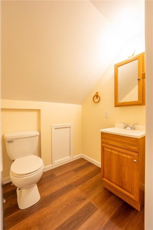 bathroom with toilet, vanity, vaulted ceiling, and hardwood / wood-style flooring