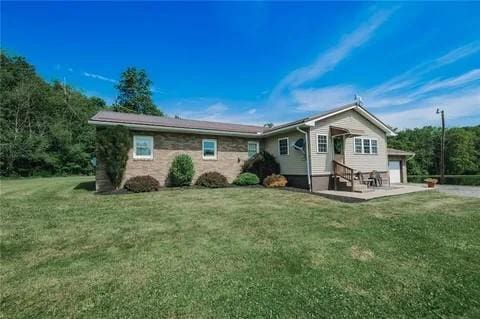 rear view of property featuring a garage and a yard