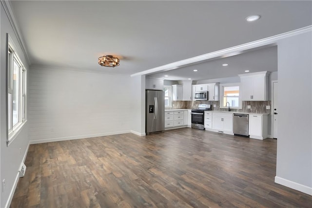 kitchen with white cabinetry, stainless steel appliances, tasteful backsplash, sink, and ornamental molding