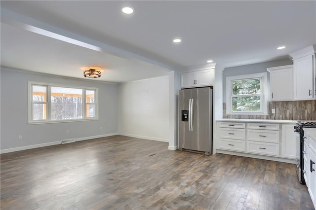 kitchen with dark wood-type flooring, appliances with stainless steel finishes, white cabinetry, and tasteful backsplash