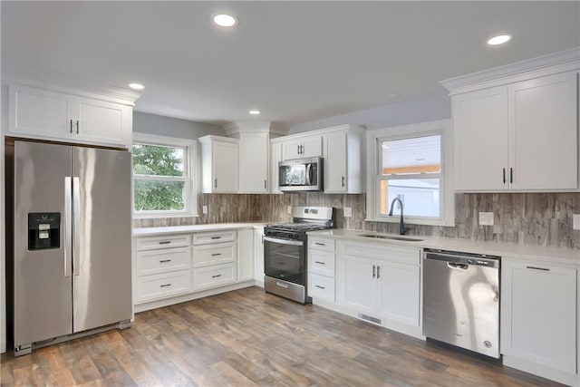 kitchen with backsplash, sink, white cabinetry, and appliances with stainless steel finishes