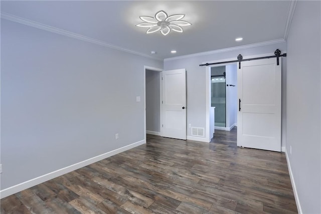 unfurnished bedroom featuring a barn door, dark hardwood / wood-style floors, and ornamental molding