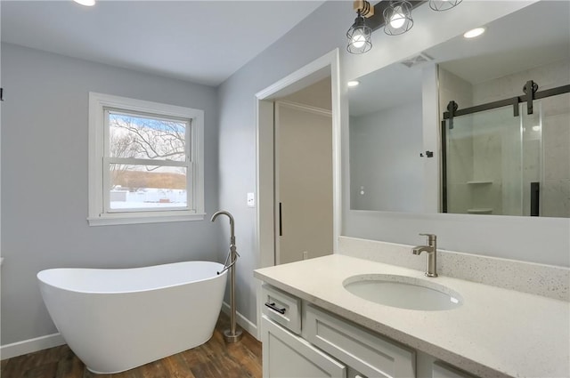 bathroom featuring plus walk in shower, hardwood / wood-style flooring, and vanity