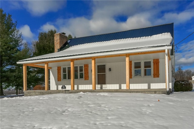 snow covered rear of property with a porch