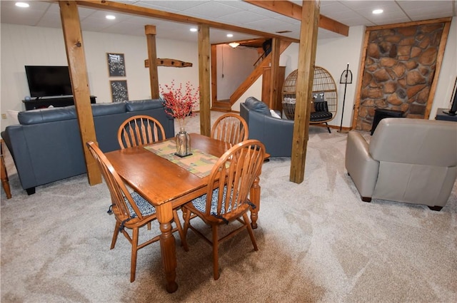 dining area featuring light colored carpet, a paneled ceiling, and a fireplace