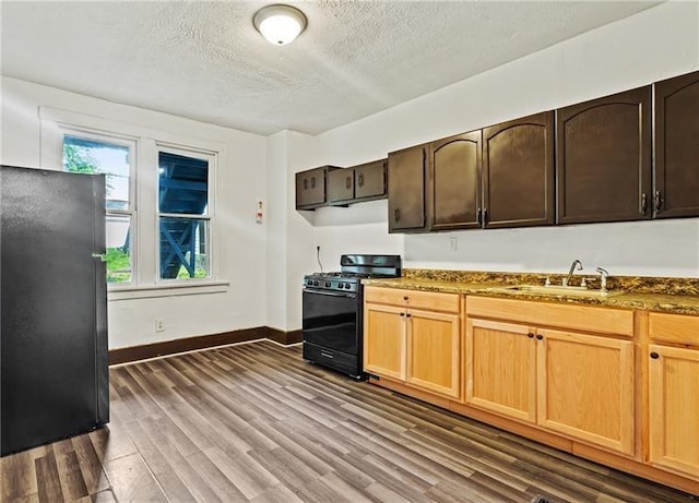 kitchen featuring a textured ceiling, black gas range oven, dark hardwood / wood-style flooring, dark stone countertops, and sink