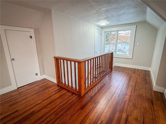 bonus room featuring vaulted ceiling, dark wood-type flooring, and a textured ceiling