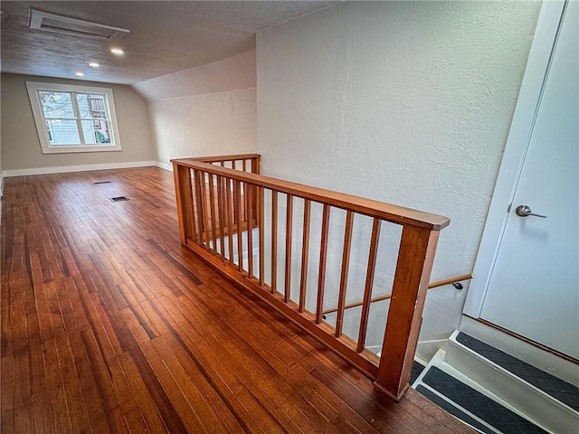 staircase featuring vaulted ceiling, a textured ceiling, and hardwood / wood-style floors