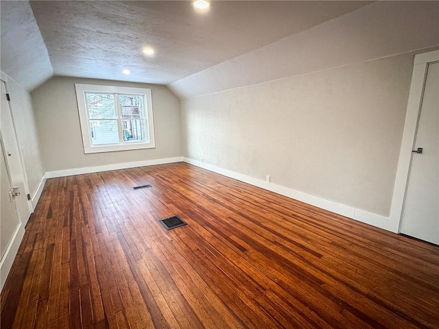 bonus room with a textured ceiling, lofted ceiling, and hardwood / wood-style floors