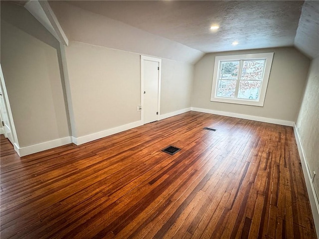 bonus room featuring vaulted ceiling, dark wood-type flooring, and a textured ceiling