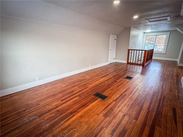 additional living space featuring vaulted ceiling and dark hardwood / wood-style flooring