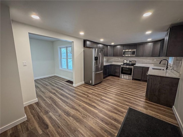 kitchen featuring dark hardwood / wood-style floors, decorative backsplash, sink, dark brown cabinetry, and stainless steel appliances