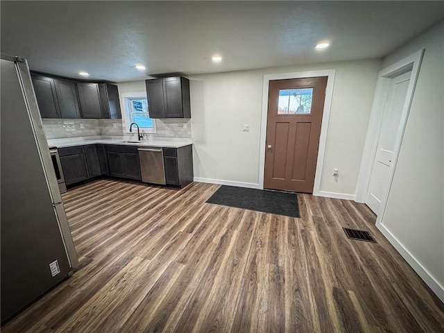 kitchen featuring tasteful backsplash, appliances with stainless steel finishes, sink, and dark wood-type flooring