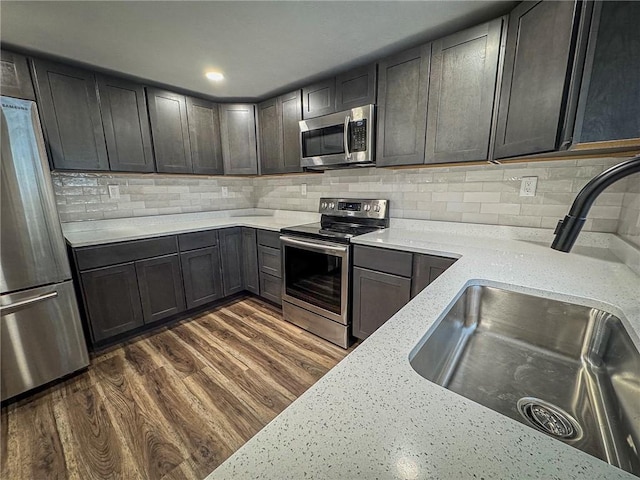 kitchen featuring light stone countertops, dark wood-type flooring, stainless steel appliances, and sink