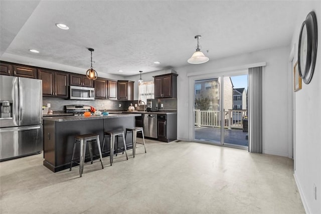 kitchen featuring hanging light fixtures, decorative backsplash, a kitchen island, and appliances with stainless steel finishes