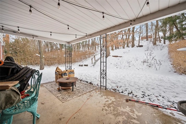 snow covered patio featuring an outdoor fire pit