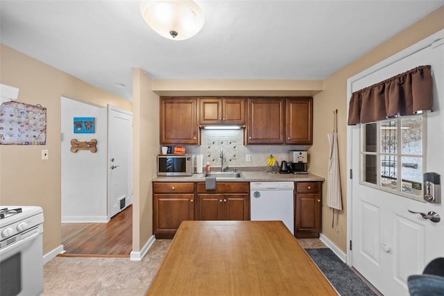 kitchen with light tile patterned flooring, sink, white appliances, and tasteful backsplash