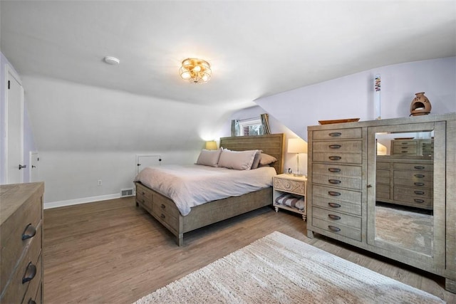 bedroom with wood-type flooring and vaulted ceiling