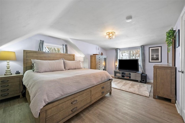 bedroom featuring hardwood / wood-style flooring, multiple windows, and vaulted ceiling