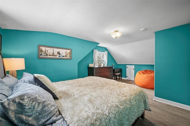 bedroom with vaulted ceiling and hardwood / wood-style flooring