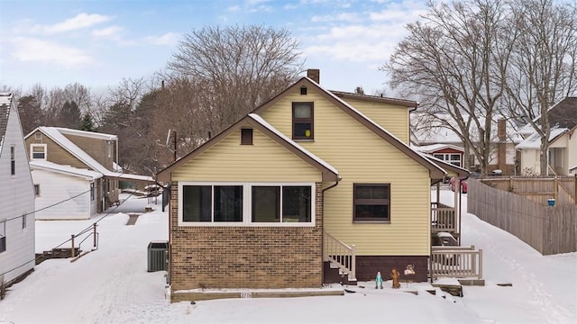 snow covered house featuring cooling unit