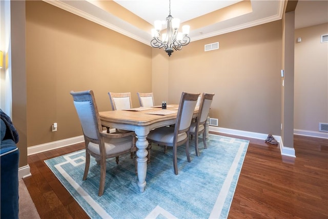 dining area with a chandelier, a raised ceiling, and dark hardwood / wood-style floors