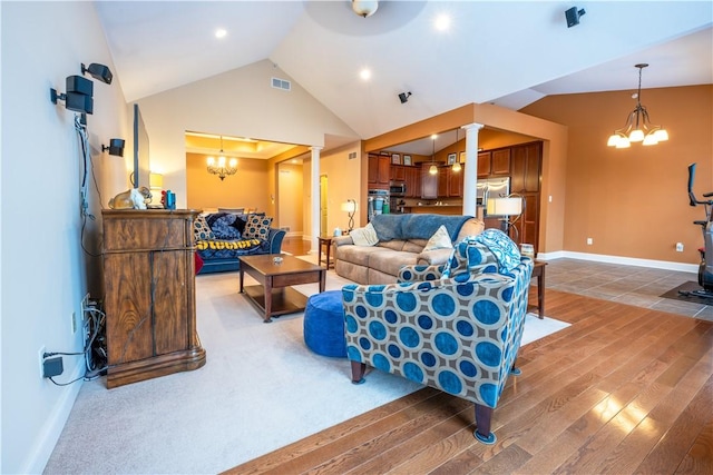 living room with ornate columns, an inviting chandelier, lofted ceiling, and wood-type flooring