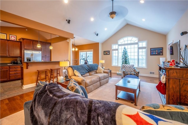 living room featuring light wood-type flooring, vaulted ceiling, and ceiling fan with notable chandelier