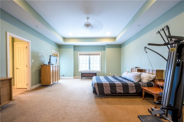 bedroom with light carpet, ceiling fan, and a raised ceiling