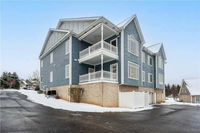 snow covered property with central air condition unit and a balcony