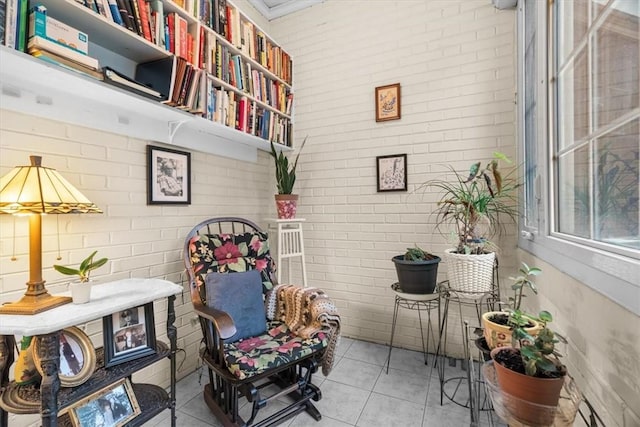 sitting room with brick wall and light tile patterned floors