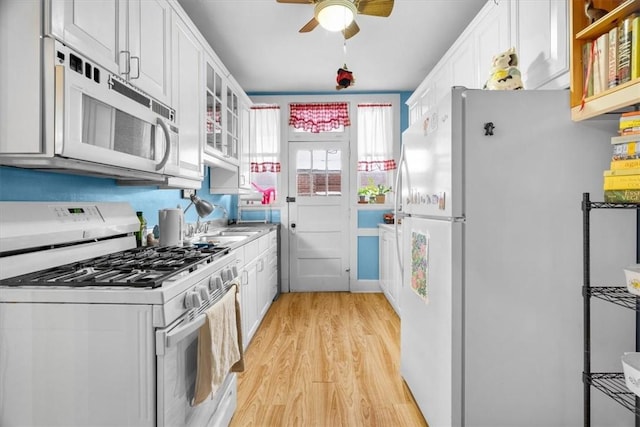 kitchen with white cabinetry, sink, light hardwood / wood-style floors, and white appliances