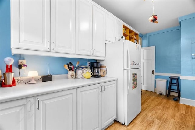 kitchen with white cabinetry, white fridge, and light wood-type flooring