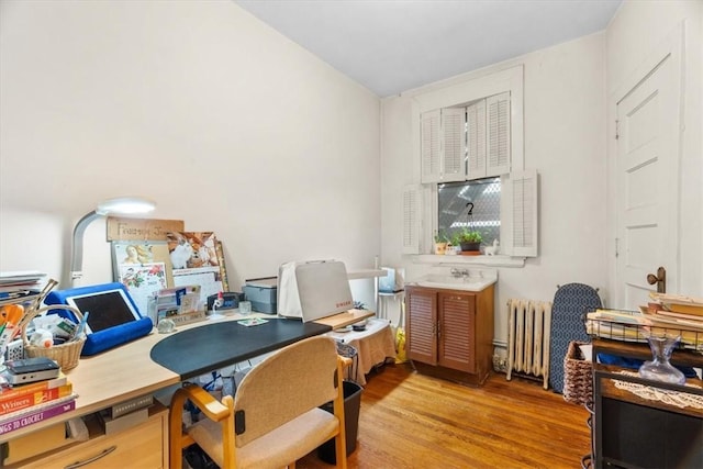 office with radiator heating unit and light wood-type flooring