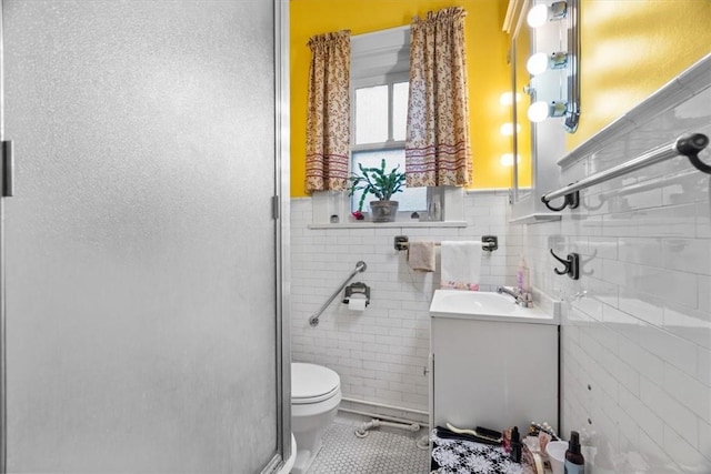 bathroom with toilet, a shower with door, tile patterned flooring, tile walls, and vanity