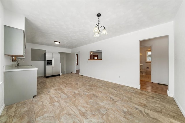 unfurnished living room featuring a chandelier, sink, and a textured ceiling