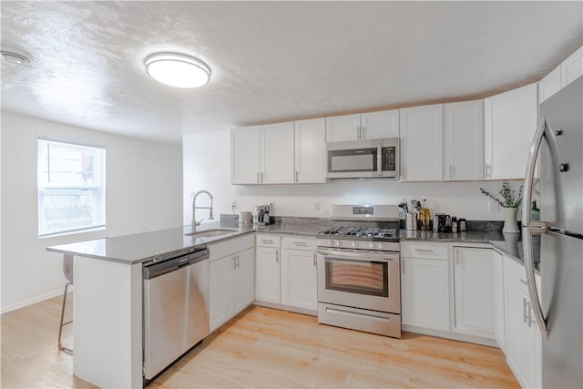 kitchen with sink, white cabinets, appliances with stainless steel finishes, and kitchen peninsula