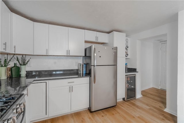 kitchen with light wood-type flooring, appliances with stainless steel finishes, wine cooler, and white cabinetry