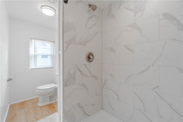 bathroom featuring toilet, tiled shower, and hardwood / wood-style flooring